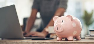 Finance, banking and saving money with piggybank, investing and planning while working on a laptop in an office at work